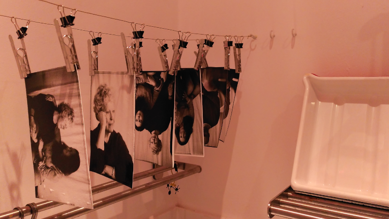 Photographic prints hanging to dry in a darkroom lit by a red safe-ligfht